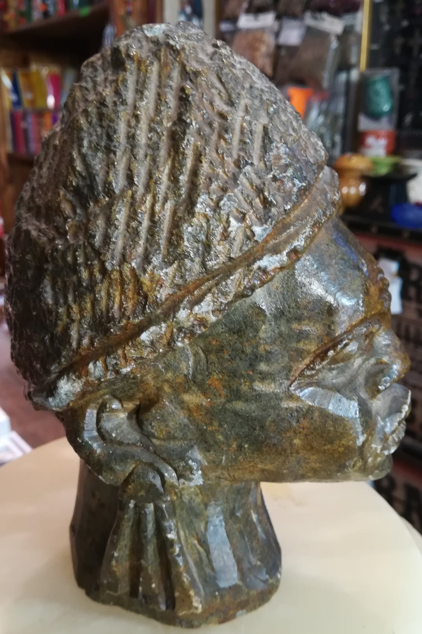 Busto masculino africano em pedra verde serpentina, esculpido do pescoço para cima, mostrando pequenos toques naturais do tempo na cabeça.