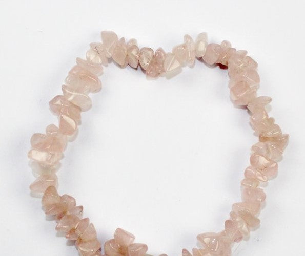 Pulseira elástica feminina feita com chips de pedra natural Quartzo Rosa em tons rosa pálido e suave sobre um fundo neutro.