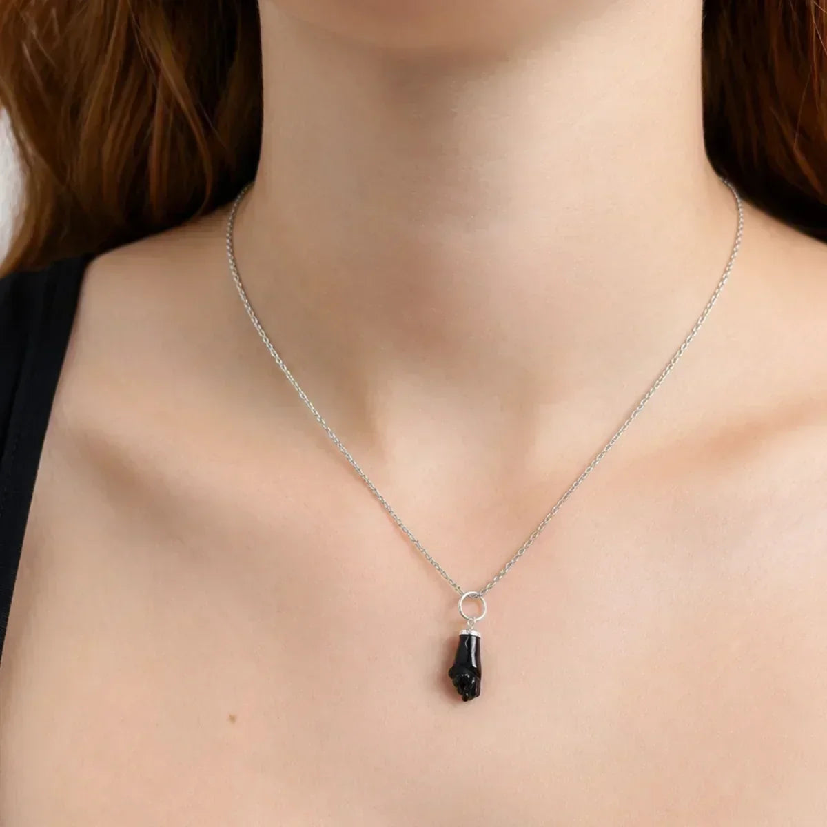 Mulher a usar um fio com pendente de figa ao peito como amuleto de proteção contra o mau-olhado.
