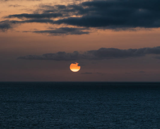 Lua encarnada refletida no mar ao fundo do pôr do sol místico.