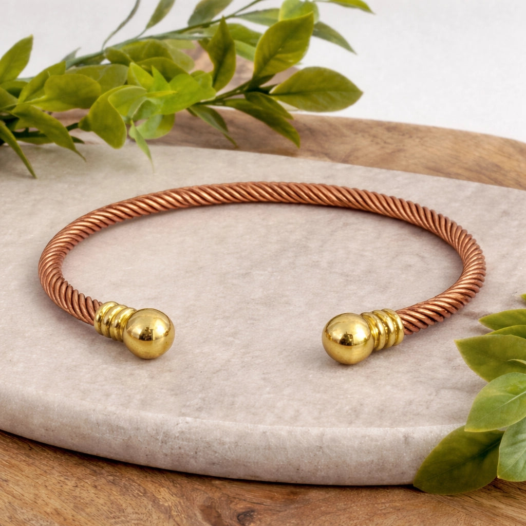 Pulseira de grampo trançada em cobre e latão com pequenas bolas douradas nas extremidades
