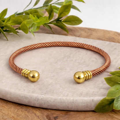 Pulseira de grampo trançada em cobre e latão com pequenas bolas douradas nas extremidades