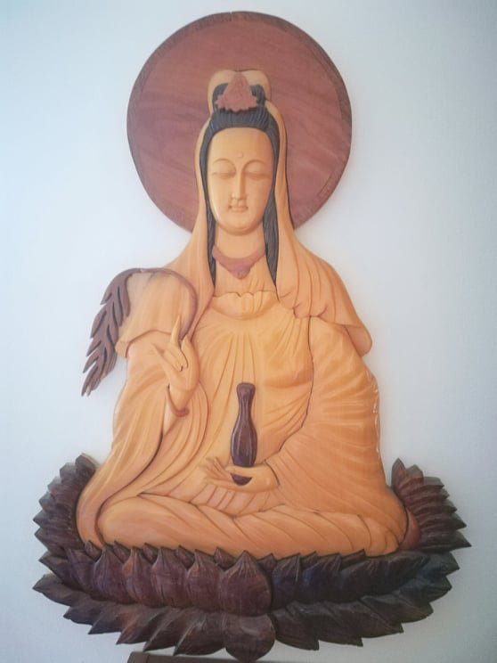 Placa retangular em madeira nobre esculpida à mão com a imagem da Deusa Kuan Yin em tons de castanho e ocre dourado 60x40cm.