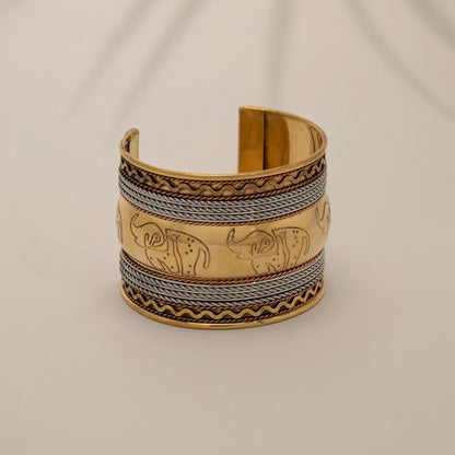 "Pulseira de braço artesanal em latão e cobre, com design em relevo de elefantes. Peça premium de estilo boho-chic com acabamento metálico misto."