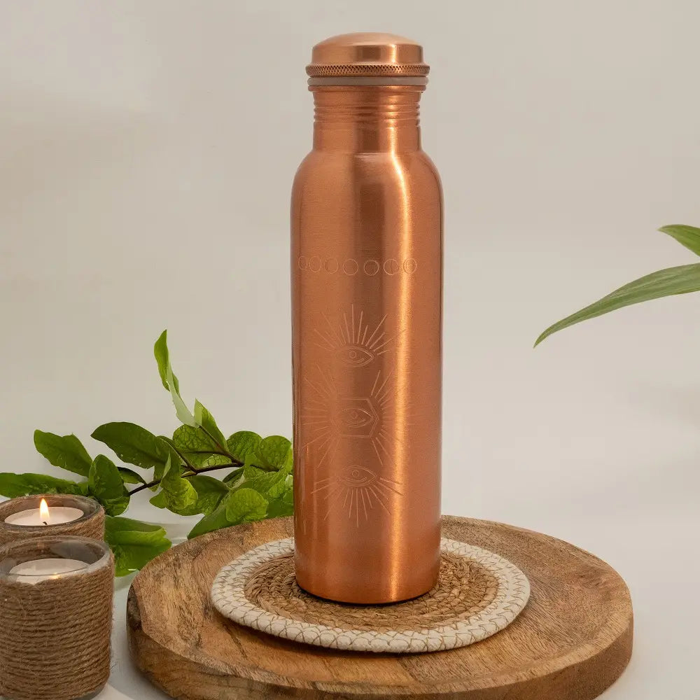 Garrafa de água de cobre puro pesada com padrão de sol gravado e capacidade de 950 ml vista de frente.