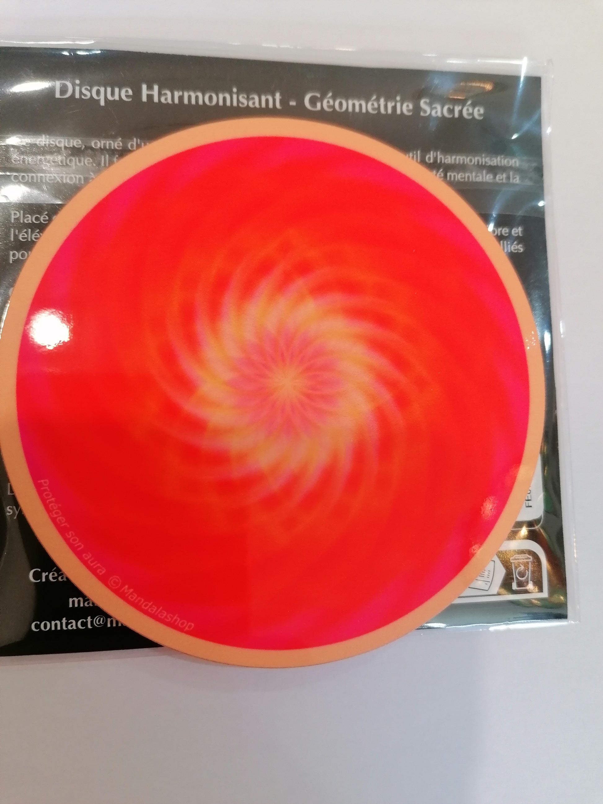 Disco de geometria sagrada com mandala laranja e vórtice central para proteção da aura.