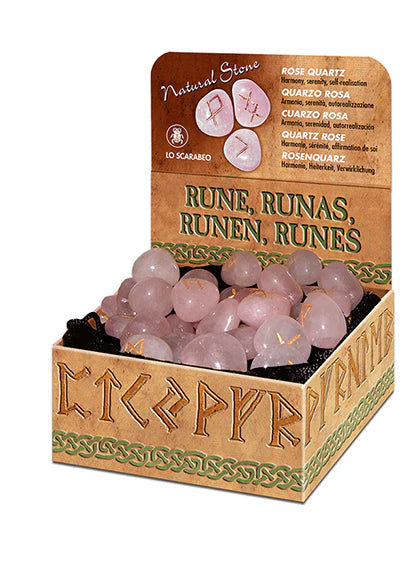 Conjunto de runas de quartzo rosa natural esculpidas com símbolos dourados sobre um fundo claro.